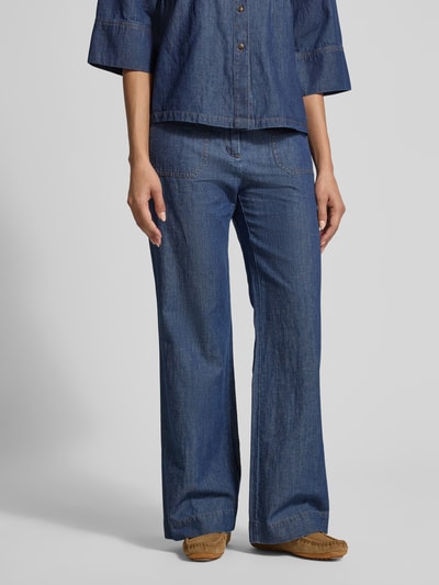 Frauenmodel trägt Flared Hose mit aufgesetzten Taschen von Jake*s Collection in dunklem Blau, sichtbare Struktur, Ganzkörperansicht von vorne. Flared Cut, Gesäßtaschen, Knopf- und Reißverschluss, Bundweite 40 cm, Innenbeinlänge 79 cm.