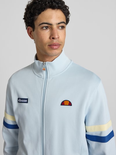 Männermodel trägt Sweatjacke aus Baumwoll-Mix Modell 'ROMA' von Ellesse in Hellblau mit Marken-Details, Nahaufnahme Oberkörper.