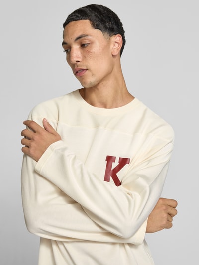 Männermodel trägt Regular Fit Longsleeve aus Viskose-Mix von Kenzo in Creme mit rotem Label-Print, Rundhalsausschnitt, Nahaufnahme Oberkörper.