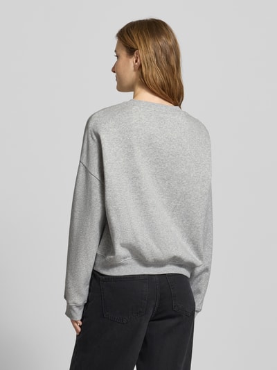 Modelka kobieca ma na sobie Oversized Sweatshirt aus Baumwoll-Mix Modell 'SWEAT LIFE' od Only, jednolity kolor szary, długi rękaw, bawełniany materiał sweat, widok całej sylwetki z tyłu.