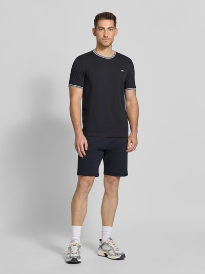 Männermodel trägt Sweatshorts mit Eingrifftaschen von Christian Berg Men in Dunkelblau, Reine Baumwolle, Regular-Fit, Label-Detail, Ganzkörperansicht von vorne. Bundweite 41 cm, Innenbeinlänge 22 cm Größe M.
