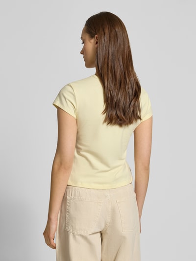 Frauenmodel trägt T-shirt mit Rundhalsausschnitt und Label-Print von Calvin Klein Jeans, mieszanka bawełny i elastanu, krój slim fit, okrągły dekolt, nadruk z logo, długość tyłu w rozmiarze S: 42 cm, jasny żółty, gładka tekstura, widok całej sylwetki z tyłu.