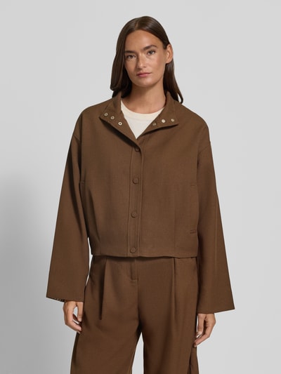 Modelka nosi Jacke mit Stehkragen Modell 'DATING' od SUNCOO PARIS w brązowym kolorze, materiał z dodatkiem wiskozy, krój regular fit, przód na guziki, długość pleców w rozmiarze S 56 cm, szerokość ramion w rozmiarze S 42 cm, szerokość klatki piersiowej w rozmiarze S 61 cm, długość rękawa w rozmiarze S 55 cm; pełny widok z przodu.