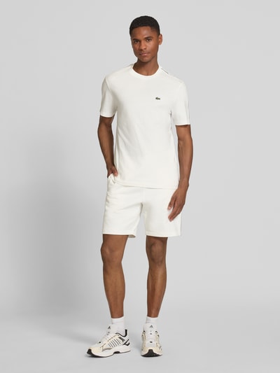 Męski model nosi Regular Fit T-Shirt aus reiner Baumwolle von Lacoste, gładki, biały, krótki rękaw, dekolt okrągły, label-tape, czysta bawełna, pełny widok z przodu
