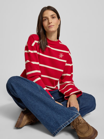 Frauenmodel trägt Relaxed Fit Sweatshirt aus Baumwoll-Mix von Tommy Hilfiger mit roten und weißen Streifen, Logo-Stitching, Ganzkörperansicht von vorne.