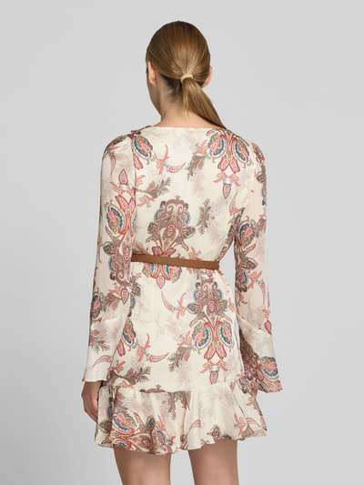 Vrouwenmodel draagt Minikleid met Rüschenbesatz van GUESS, getailleerde pasvorm, met ruches, V-hals, met lange mouwen, ruglengte maat S 83 cm, borstwijdte maat S 42 cm, mouwlengte maat S 62 cm, kleurrijk paisley-motief op licht stoffen ondergrond. Ganzkörperansicht Rückansicht.
