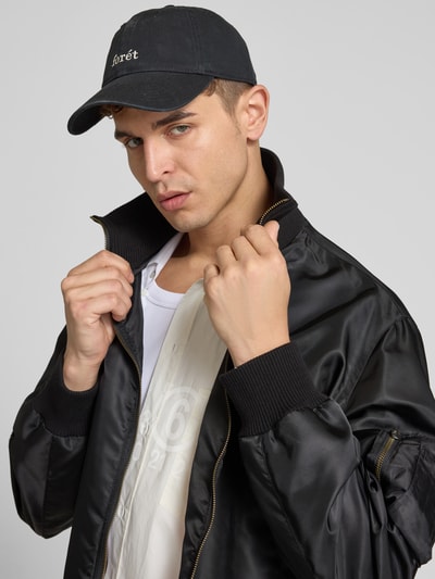 Männermodel trägt Basecap mit Label-Stitching von Forét in tiefem Blau, Denim-Look, sportliches Design, Nahaufnahme Oberkörper.