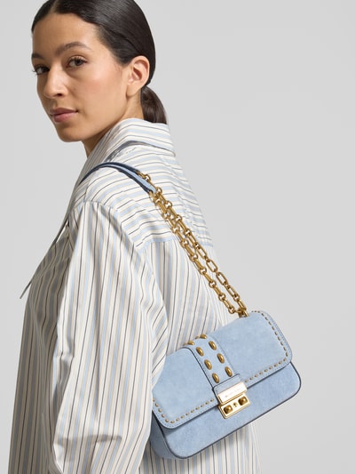 Frauenmodel trägt Handtasche mit Schulterriemen Modell 'TRIBECA' von MICHAEL Michael Kors, hellblau, goldfarbene Details, Ganzkörperansicht Rückansicht. Hauptfach mit Überschlag, Klickverschluss, Schulterriemen 109 cm, Maße 23x13x7 cm.