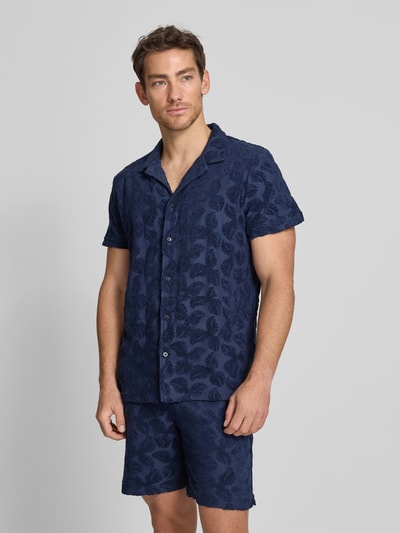 Männermodel trägt Regular Fit Freizeithemd Modell 'TERRY' von Scotch & Soda aus Baumwoll-Mix mit Reverskragen und Knopfleiste, Ganzkörperansicht von vorne. Rückenlänge bei Größe M: 72 cm, Schulterbreite: 50 cm, Ärmellänge: 22 cm. Hemd mit dunklem blauen Muster und strukturierter Oberfläche.