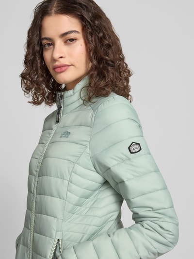 Frauenmodel trägt Steppjacke mit Logo-Stitching Modell 'FUJI' von Superdry in Mint, Reißverschluss, Seitliche Reißverschlusstaschen, Nahaufnahme Oberkörper.
