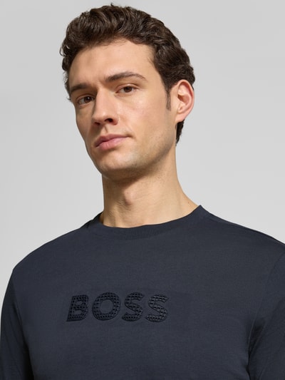 Männermodel trägt Regular Fit T-Shirt aus reiner Baumwolle Modell 'TS_TERRACE' von BOSS Green, unifarben, 3D-Label Print, Nahaufnahme Oberkörper.