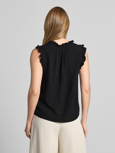 Männermodel trägt Regular Fit Blusentop aus reiner Viskose Modell 'ALBA' von Vero Moda, czarna gładka tkanina, krój regular fit, bez rękawów, falbanki, z wiązanym detalem, widok całej sylwetki z tyłu.