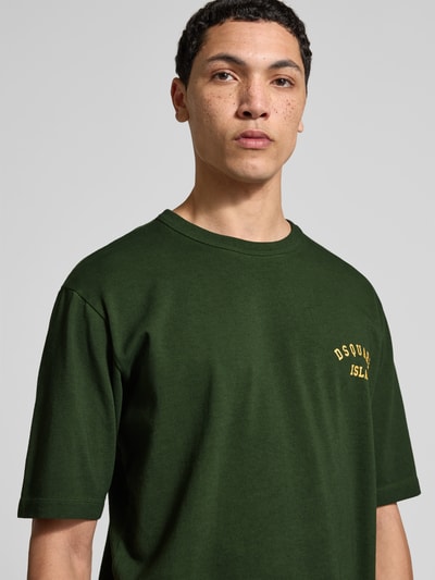 Männermodel trägt Loose Fit T-Shirt aus reiner Baumwolle von Dsquared2, dunkelgrün mit Label-Print, kurzärmelig, Nahaufnahme Oberkörper.