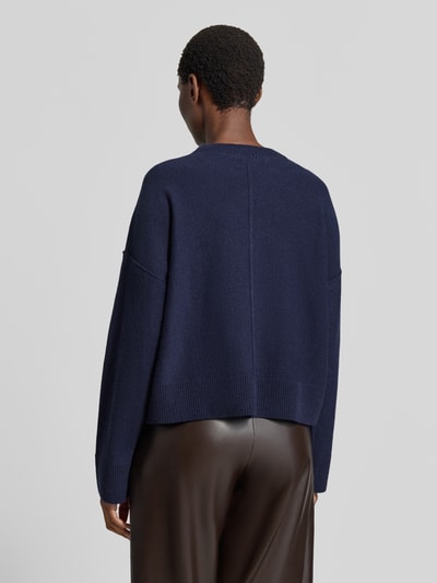 Frauenmodel trägt Wollpullover aus Schurwoll-Baumwoll-Mix von Lanius in Dunkelblau mit Ziernaht und gerippten Abschlüssen, lockere Passform, ganzkörperansicht Rückansicht, Rückenlänge 52 cm, Ärmellänge 48 cm.