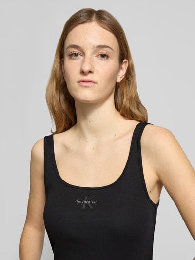 Kobiece modelka nosi Slim Fit Top z nadrukiem z logo Model 'Scoop' od Calvin Klein Jeans, okrągły dekolt, damski top, krój slim fit, długość tyłu w rozmiarze S: 42 cm, zbliżenie na górną część ciała