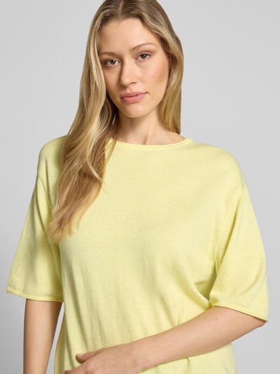 Modelka nosi Oversized Pullover aus Baumwoll-Kaschmir-Mix von Tom Tailor, efekt: jednolity kolor, krój oversized, okrągły dekolt, krótki rękaw, zrolowany brzeg, dzianina, mieszanka bawełny i kaszmiru, jasny żółty, miękka tekstura, zbliżenie górnej części ciała
