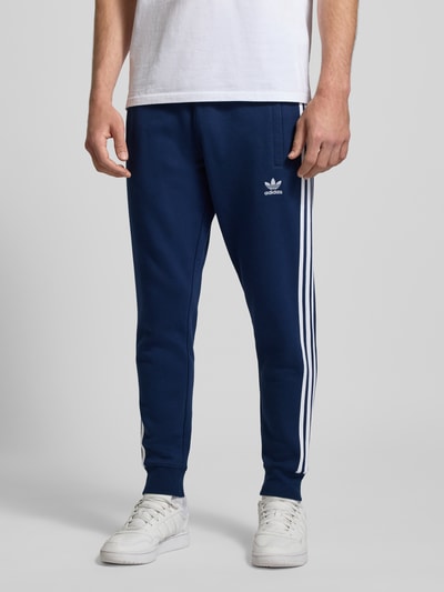 Männermodel trägt Sweatpants mit elastischem Bund von adidas Originals, Baumwoll-Mix, Lockerer-Schnitt, Eingrifftaschen, Ganzkörperansicht von vorne.