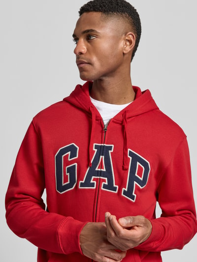 Männermodel trägt Sweatjacke mit Logo und Känguru-Tasche von GAP in Rot, Baumwoll-Mix, Regular-Fit, Nahaufnahme Oberkörper.