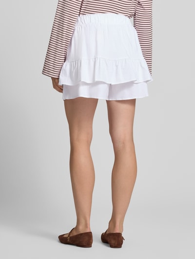 Frauenmodel trägt weißen Ausgestellter Skort aus Leinen-Baumwoll-Mix Modell 'PIPPA' von VILLA SOPHIE, abgestufte Rüschendetails, lockere Stoffstruktur, Ganzkörperansicht Rückansicht.