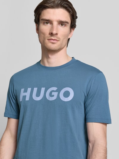 Mężczyzna nosi Regular Fit T-Shirt aus reiner Baumwolle Modell 'DULIVIO' von HUGO, kolor jednolity, nadruk z logo, jersey, ujęcie: zbliżenie na górną część ciała.