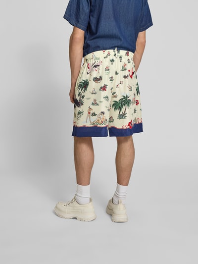 Männermodel trägt Seidenshorts aus reiner Seide von Dsquared2 mit lockerer Passform, elastischem Bund, tropischem Print, glänzende Optik, Ganzkörperansicht Rückansicht.