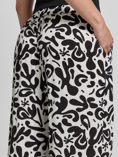 Frauenmodel trägt Weite HOSE aus reiner Viskose Modell 'BARRI' von Pieces mit grafischem Allover-Muster, seitliche Eingrifftaschen, Nahaufnahme Rückansicht.