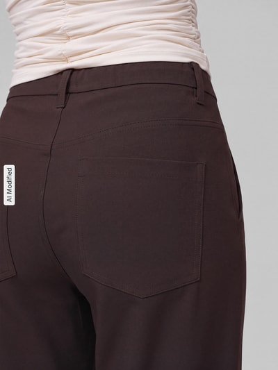 Frauenmodel trägt Gerade Hose mit Gürtelschlaufen Modell 'Baggy Smart' von MAC, Damen Gerade Hose, dunkelbraune Farbe, glatte Textur, Nahaufnahme Rückansicht, KI-modifiziertes Bild.