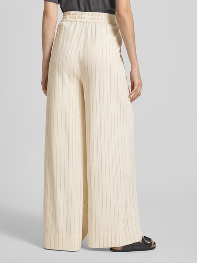 Frauenmodel trägt Loose Fit Pants mit Eingrifftaschen Modell 'tascha' von Gestuz, Viskose-Mix mit Leinen-Anteil, ausgestellter Schnitt, Bundweite 38 cm, Innenbeinlänge 81 cm, cremefarben mit feinen Streifen, strukturierte Stofftextur, Ganzkörperansicht Rückansicht.