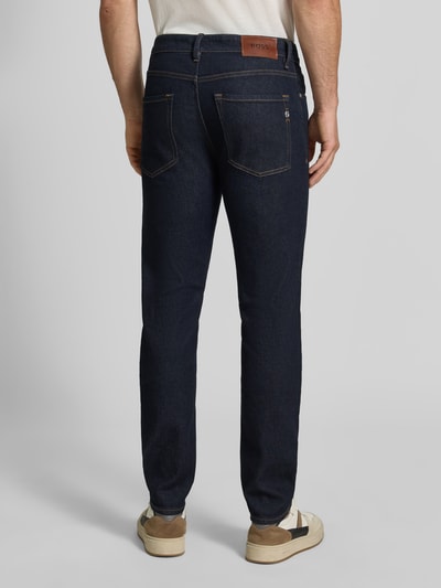 Männermodel trägt Slim Fit Jeans aus Baumwoll-Mix Modell 'Delaware' von BOSS in Dunkelblau, sichtbare Kontrastnähte, Ganzkörperansicht Rückansicht. Herren Slim Fit Jeans von BOSS.