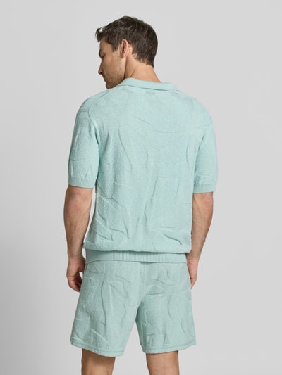 Männermodel trägt Relaxed Fit Poloshirt aus reiner Baumwolle Modell 'ASURFO' von BOSS Orange, Optik: Unifarben, Struktur, Ganzkörperansicht Rückansicht.
