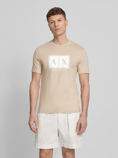 Männermodel trägt T-Shirt mit Logo und Rundhalsausschnitt von ARMANI EXCHANGE aus reiner Baumwolle, Regular-Fit, sandfarben, Ganzkörperansicht von vorne. Rückenlänge bei Größe M: 71 cm.