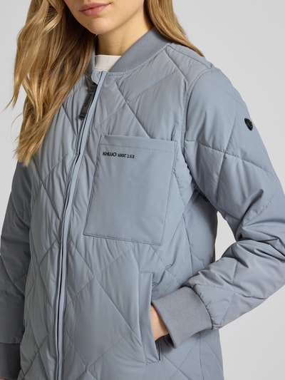 Kobiece model prezentuje Steppjacke mit Zweiwege-Reißverschluss Modell 'YMAL2' od khujo, jasno niebieski kolor, krój regular fit, stebnowania, kieszenie, detaliczny widok na górną część, Nahaufnahme górnej części ciała. Szerokość w rozmiarze S: 50 cm, długość tyłu: 92 cm, szerokość ramion: 38 cm, długość rękawa: 60 cm.