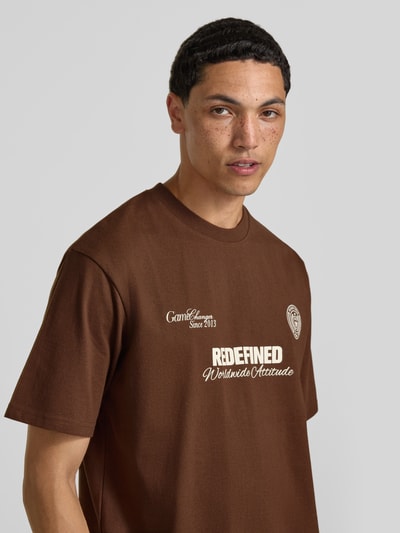 Männermodel trägt T-Shirt mit Statement-Print und Rundhalsausschnitt von Redefined Rebel, Braun, Baumwoll-Mix, Relaxed-Fit, Nahaufnahme Oberkörper.