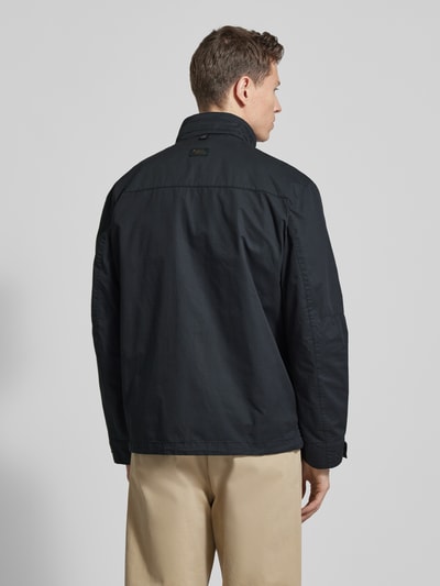 Mężczyznamodel nosi Jacke aus reiner Baumwolle mit Brusttaschen von camel active, prosta forma, czarny kolor, bawełniana tekstura, widok całej sylwetki z tyłu. Szerokość w rozmiarze 50: 52 cm, długość tyłu: 73 cm, szerokość klatki piersiowej: 58 cm, długość rękawa: 64 cm.