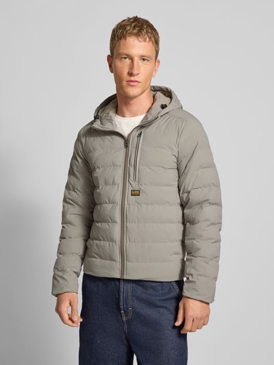 Männermodel trägt graue Steppjacke mit Brusttasche und Label-Detail Modell 'Foundation' von G-Star, Regular-Fit, Kapuze, Reißverschluss, Ganzkörperansicht von vorne, Rückenlänge 70 cm, Schulterbreite 46 cm, Brustweite 56 cm, Ärmellänge 70 cm.