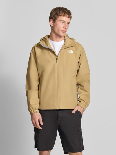 Männermodel trägt Jacke mit Kapuze von The North Face in Beige, Regular-Fit, mit Reißverschlusstaschen und Label-Print, Ganzkörperansicht von vorne. Rückenlänge 76 cm, Schulterbreite 48 cm, Brustweite 68 cm, Ärmellänge 68 cm, Größe L.