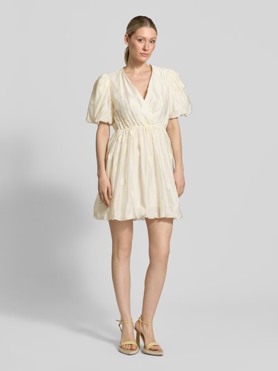 Frauenmodel trägt Minikleid mit V-Ausschnitt Modell 'CHAYA' von SUNCOO PARIS, cremefarben, Lyocell-Mix, Puffärmel, Taillierte Passform, Wickel-Optik, Ganzkörperansicht von vorne. Rückenlänge bei Größe S: 89 cm, Brustweite: 42 cm, Ärmellänge: 21 cm.