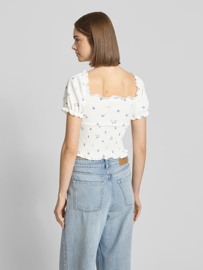 Frauenmodel trägt Slim Fit Blusentop mit Allover-Muster Modell 'HILLARY' von Only, florales Muster auf weiß, Cropped-Länge, kurzarm, Henley-Ausschnitt, ohne Kragen, Passform: Slim Fit, Ärmelabschluss mit Raffungen, Optik:Allover-Muster, Jeans, Ganzkörperansicht Rückansicht.