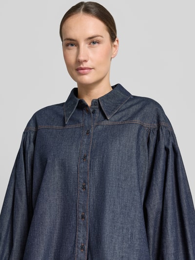 Männermodel trägt Relaxed Fit Jeansbluse Modell 'SELENI' von Drykorn aus reiner Baumwolle, ciemnoniebieski kolor, guziki, miękka faktura, kołnierz koszulowy, długość tyłu w rozmiarze 36: 64 cm, długość rękawa w rozmiarze 36: 57 cm, zbliżenie na górną część ciała.
