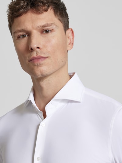 Männermodel trägt Slim Fit Business-Hemd mit Kentkragen von JOOP! Collection in Weiß, glatte Struktur, Nahaufnahme Oberkörper, Material-Mix mit Stretch-Anteil