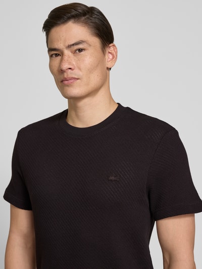 Męski model nosi Regular Fit T-Shirt aus reiner Baumwolle von Lacoste, czarny, gładki, krótki rękaw, logo, tkanina dzianinowa, zbliżenie górnej części ciała.