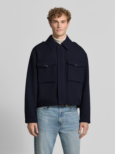 Männermodel trägt Jacke aus Viskose-Mix von Emporio Armani in Dunkelblau, Umlegekragen, Brusttaschen, gerade Passform, Ganzkörperansicht von vorne.