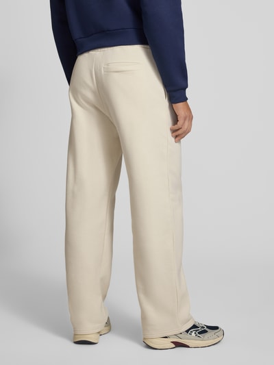 Männermodel trägt Straight Fit Sweatpants aus Baumwoll-Mix mit Label-Detail von REVIEW in Beige, sichtbar elastischer Bund, Eingrifftaschen, gerade Form, Struktur leicht texturiert, Ganzkörperansicht Rückansicht.