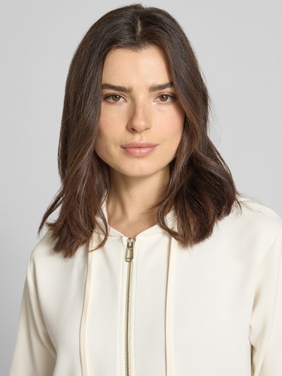 Frauenmodel trägt Sweatjacke mit Halbarm Modell 'Therese' von JOOP! in Creme, Elastischer-Material-Mix, Reißverschluss, Label-Detail, Nahaufnahme Oberkörper.