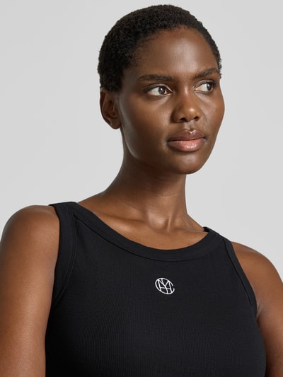 Männermodel trägt czarny top Tanktop in Ripp-Optik mit Label-Stitching Modell 'Gubbe' von MSCH Copenhagen, mieszanka bawełny i elastanu, krój regular fit, wyhaftowane logo, efekt prążkowania, Długość tyłu w rozmiarze XS/S: 54 cm, Nahaufnahme Oberkörper.