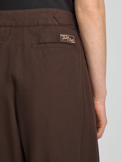 Frauenmodel trägt Wide Leg Hose mit Eingrifftaschen Modell 'QUINN' von Scotch & Soda in Braun, Baumwoll-Leinen-Mix, Detailaufnahme Rückansicht.