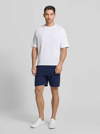 Männermodel trägt Regular Fit Sweatshorts aus reiner Baumwolle von Lacoste, Optik: Unifarben, Materialverarbeitung: Sweat, Ganzkörperansicht von vorne.