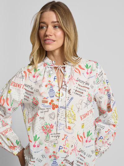 Frauenmodel trägt Regular Fit Bluse im Allover-Look mit Schnürung von Emily Van den Bergh, bunte Muster auf weißer Baumwolle, Nahaufnahme Oberkörper.