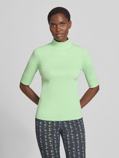 Frauenmodel trägt Slim Fit T-Shirt aus Baumwoll-Mix mit Stehkragen von Marc Cain in Mintgrün, 1/2-Arm, Ganzkörperansicht von vorne.