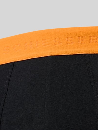 Produktfoto, Slim Fit Trunks mit Logo-Detail im 3er-Pack von Schiesser, schwarzer Stoff, oranger elastischer Bund, Baumwoll-Mix, Detailaufnahme.
